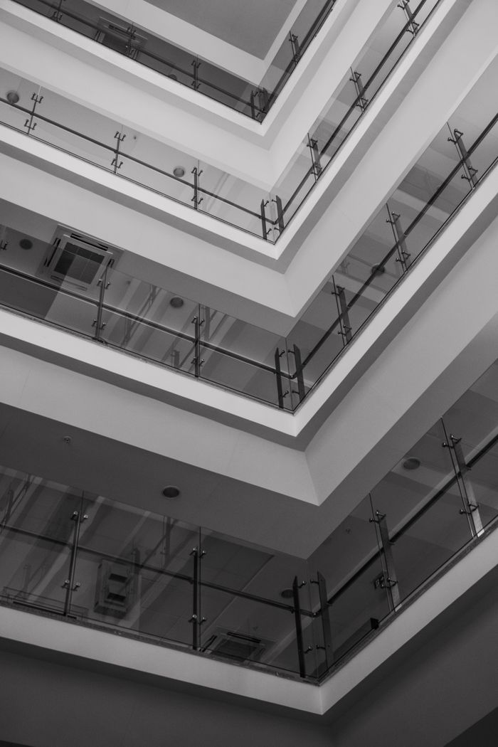 Grayscale photo of a modern building interior featuring glass railings and geometric design.