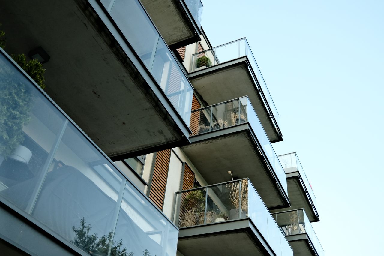 A modern residential building's glass balconies under a clear sky, showcasing contemporary architecture.