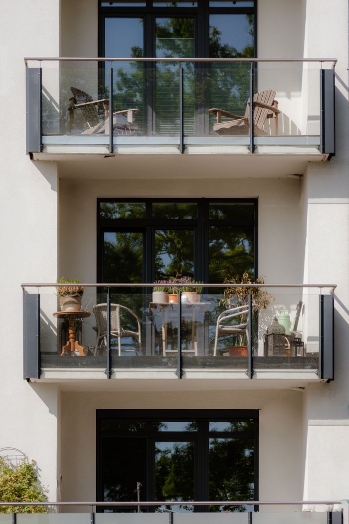 Close-up of a building's balconies with chairs and plants creating a cozy outdoor space.